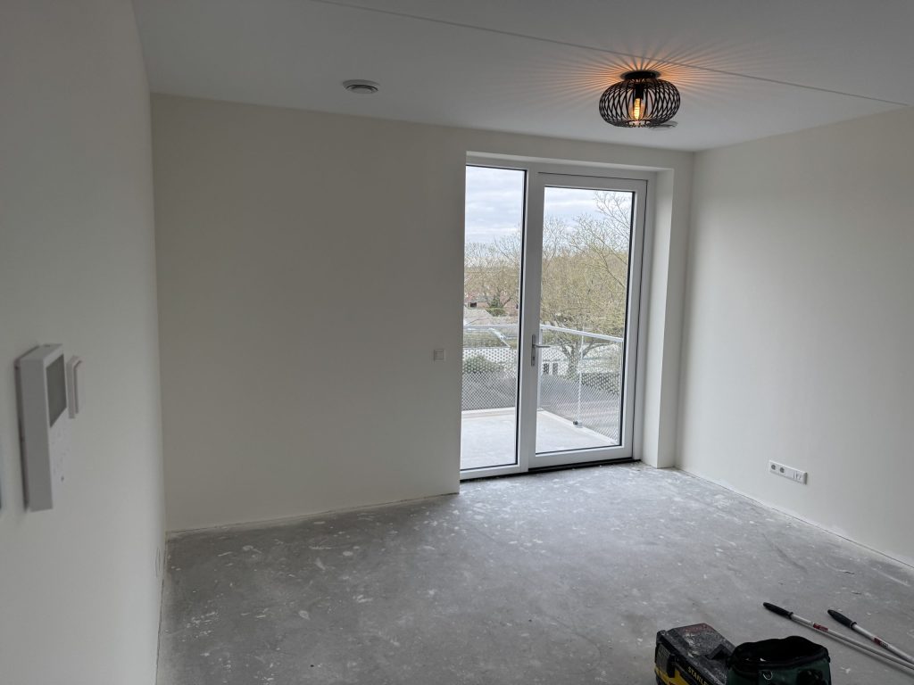 Lege kamer in een nieuw appartement met openslaande deuren naar het balkon